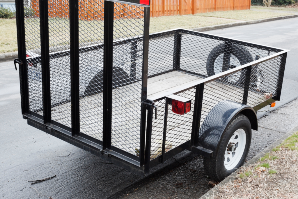 A utility trailer with a wooden deck and side blinkers. 